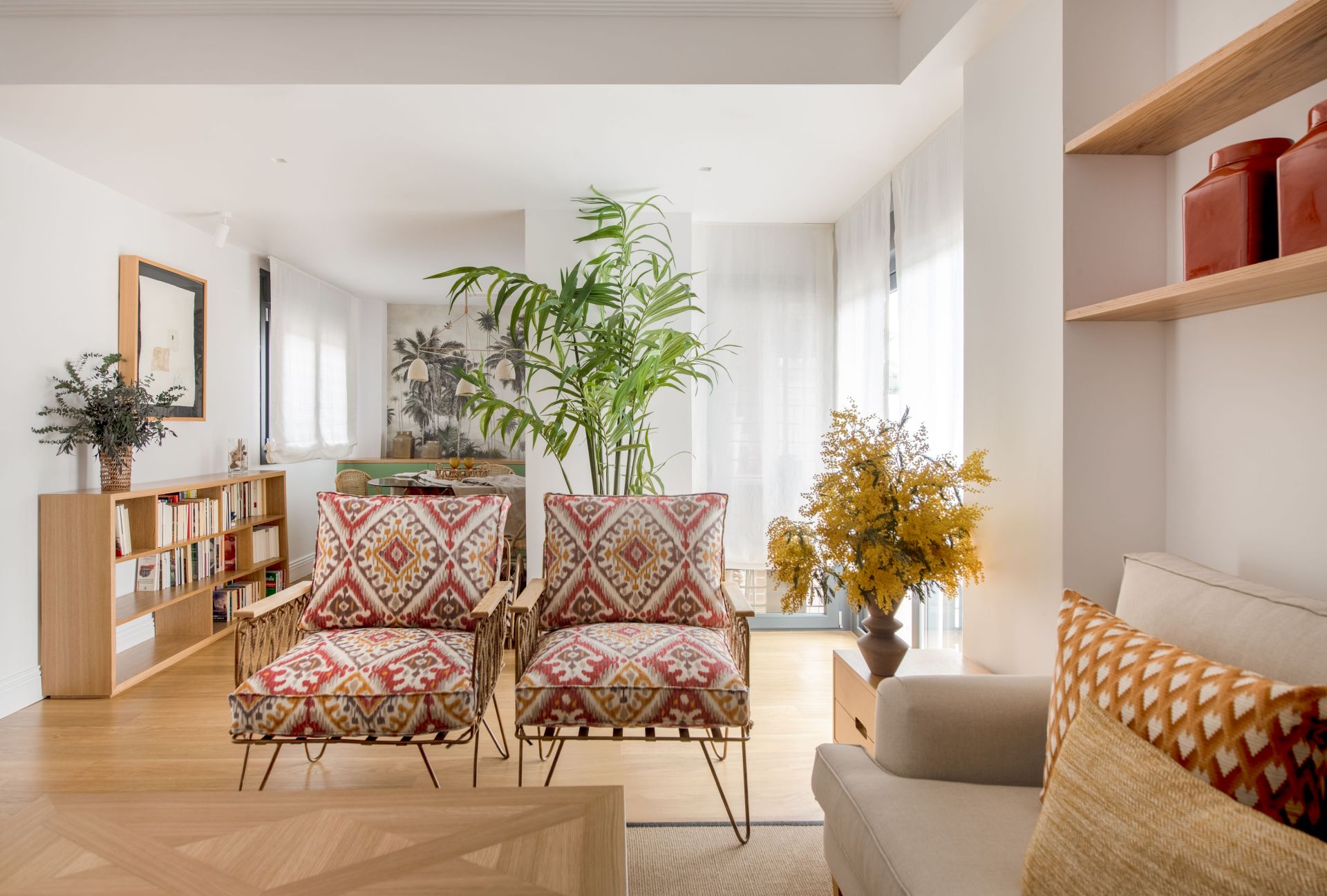 Vivienda privada reformada: salón con sillones estampados, estantería y plantas